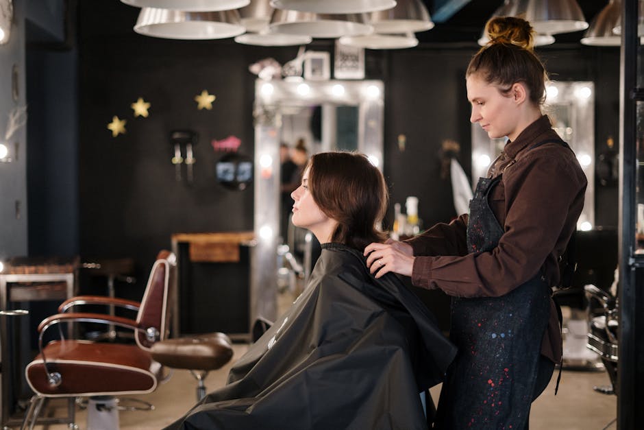 A hairstylist trims a client's hair in a modern salon setting, capturing a moment of focus