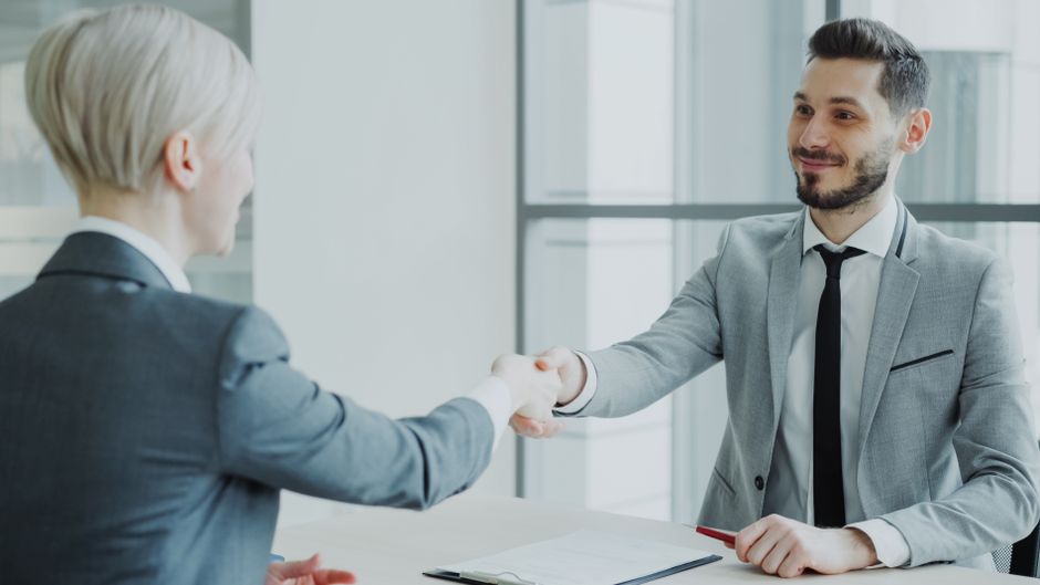 Dos profesionales dándose la mano en una oficina moderna y luminosa